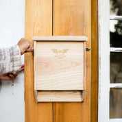 Natural cedar two-chamber bat house mounted on a wooden wall